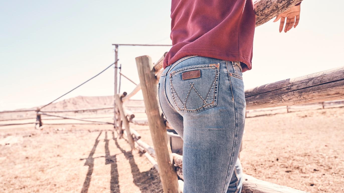 woman standing by fence in wrangler jeans